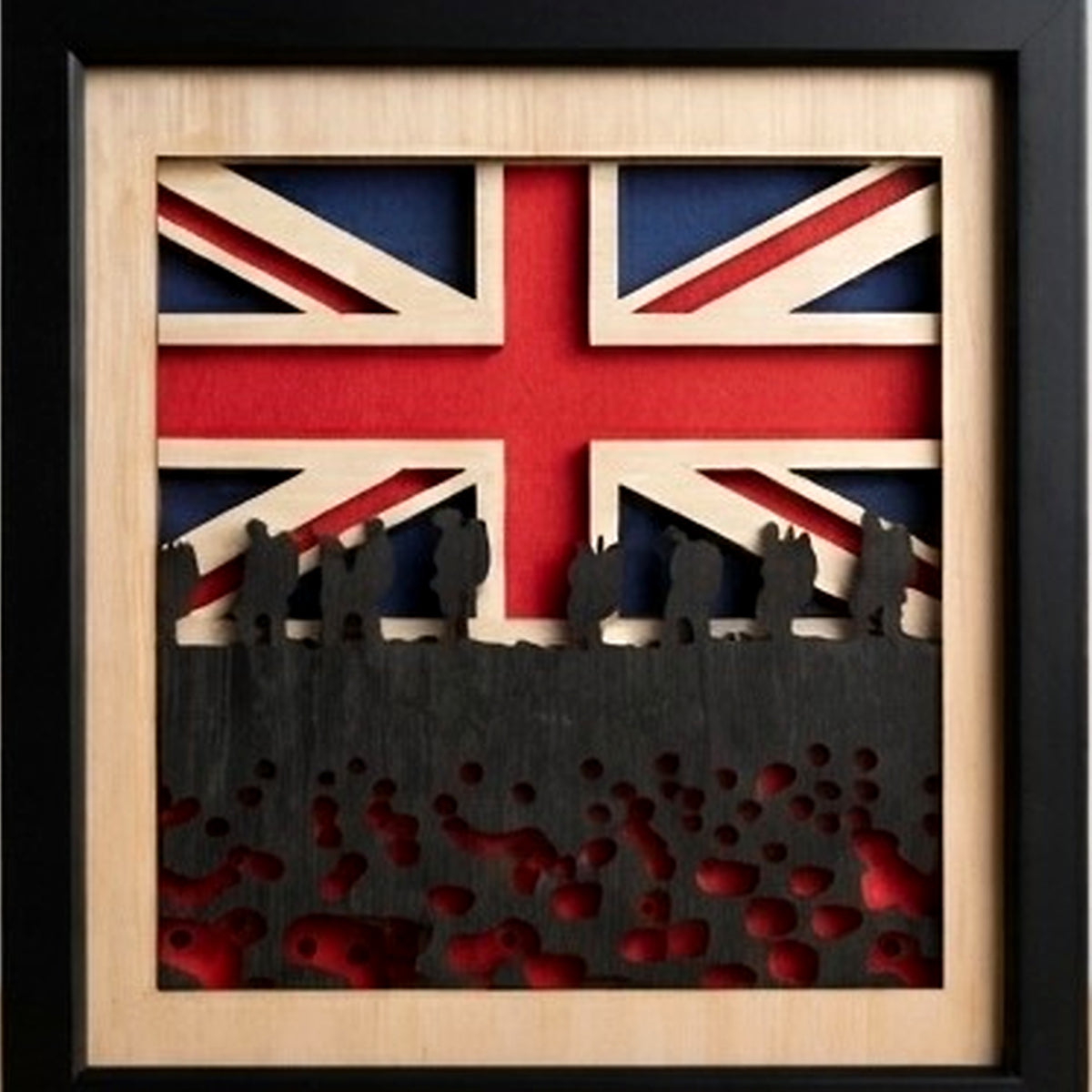 Framed wooden wall art featuring a layered Union Jack flag design with black silhouette figures and red cutout details on a light wood background, enclosed in a black frame.